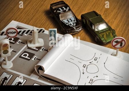 Notepad, book of traffic rules, toy cars, traffic lights and stop sign on a desk table. Studying and preparing for driving test Stock Photo