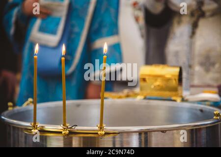 Christening in the church, candles at children baptismal font. Details in the orthodox christian church Stock Photo