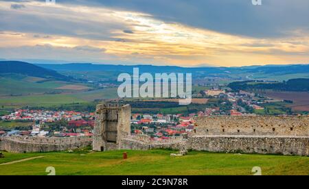 Tower and walls of the of Spis Castle ruins and the Spišské Podhradie town in the background on a cloudy afternoon. Spisska Nova Ves, Slovakia. Stock Photo