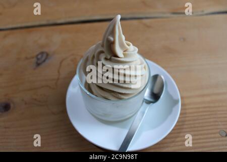 Goat's milk soft serve ice cream in a glass dessert dish, with a silver spoon Stock Photo