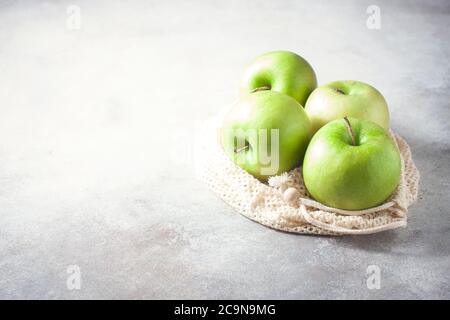 Organic green apples in reusable cotton net bag on wooden table. Eco-package, zero waste concept. Selective focus. Stock Photo