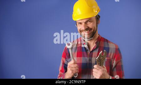 Home improvement concept. Young handyman with tools and hard hat isolated on the blu background. High quality photo Stock Photo