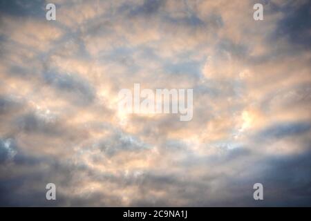Dramatic overcast sky with the gleams of the sun, in yellow and blue colours, background image. Stock Photo