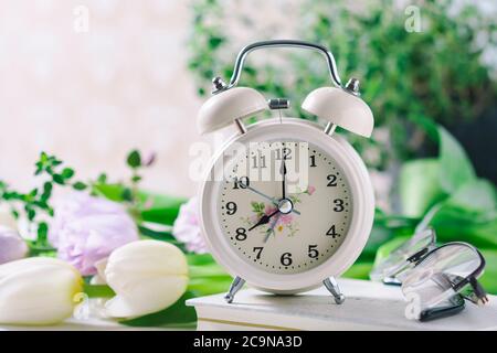 Spring flowers and retro Alarm Clock. Selective focus Stock Photo