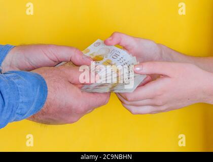 people passing money each other on yellow background Stock Photo