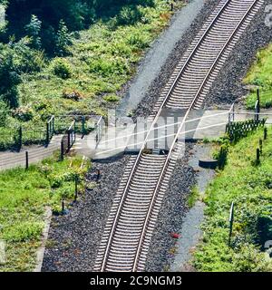View from above on a railway track, which is crossed by a footpath and cycle track. Stock Photo