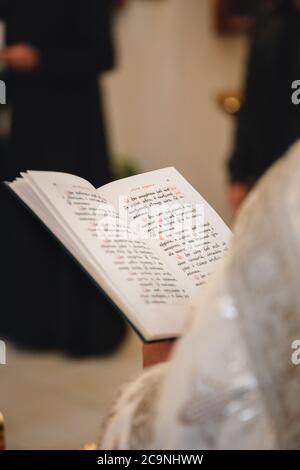 Christening in the church, priest is reading a prayer from the Bible. Details in the orthodox christian church Stock Photo