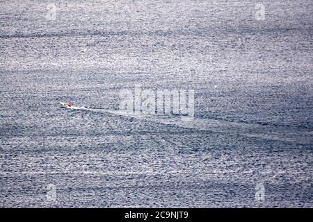 small boat on calm flat surface of ocean Stock Photo