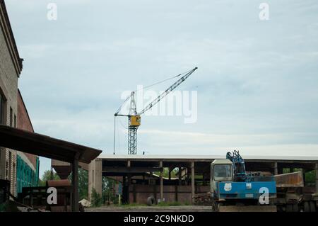 View of obsolete working machines at a small rural working brick factory. Dirty, old transport on a background of the sky, nostalgia. In a parking Stock Photo