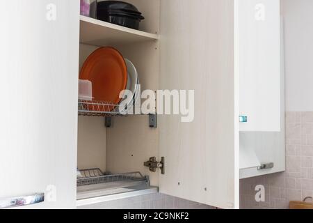 Dish drying on a metal dish rack in a kitchen cabinet Stock Photo