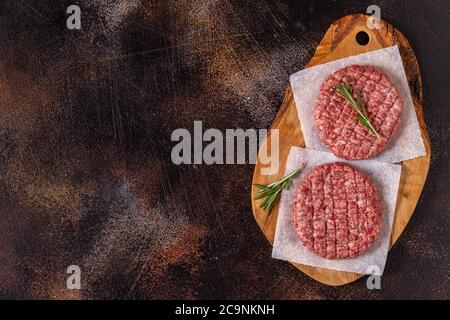 Fresh raw minced homemade grill beef burgers on wooden chopping board, top view Stock Photo