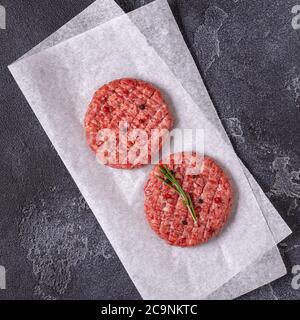 Fresh raw meat burger cutlet with herbs and spices on the black stone board, top view Stock Photo