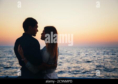 Silhouette of a couple at the beach at sunrise sky summer time, seashore summer beach at yellow blue evening horizon sea, sunset background Stock Photo