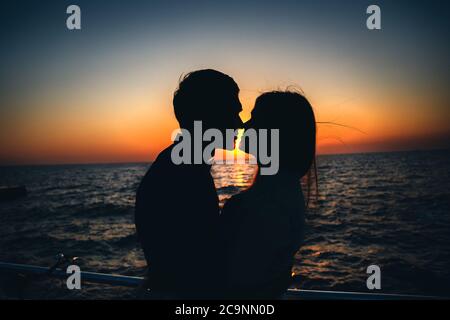 Silhouette of a couple at the beach at sunrise sky summer time, seashore summer beach at yellow blue evening horizon sea, sunset background Stock Photo