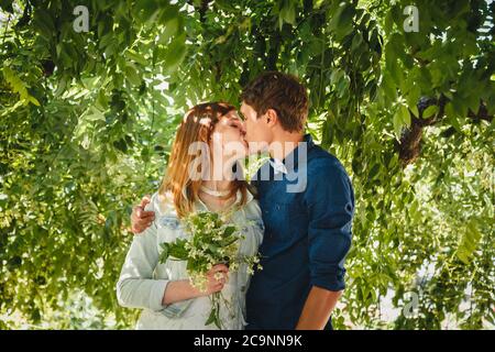 Happy stylish loving couple of hipsters hugging and kissing in a park Stock Photo