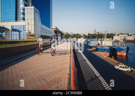 ODESSA, UKRAINE - AUGUST 06, 2015: Couple of young hipsters cycling together at the port, travel concept, summer time Stock Photo