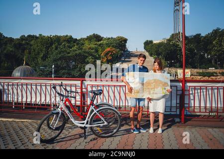 ODESSA, UKRAINE - AUGUST 06, 2015: cute young beautiful hipster couple with map, with Potemkin Stairs at background, happy smiling outdoor portrait Stock Photo