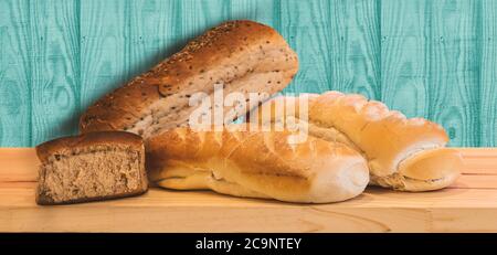 Different kinds of fresh bread on a wooden table with a mint wooden background. Fresh bread. Concept of Bakery. Close up photo with nobody. Copy space Stock Photo