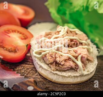 bun with tuna, tomatoes and lettuce on a cutting board Stock Photo