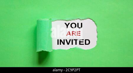 The text 'you are invited' appearing behind torn green paper. Stock Photo