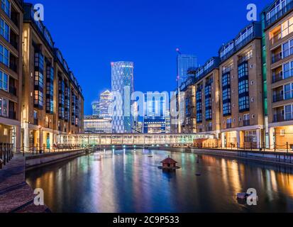 Night scene of the Canary Wharf financial buildings and residential houses reflected in the river Thames Stock Photo