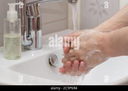 Hygiene concept cleaning hand and washing hands. Close up a man washes his hands with soap in the basin. Stock Photo