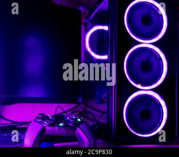 Close up of a gaming pc case and game pad with pink lighting Stock Photo