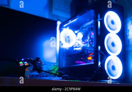 Close up of a game pad and a pc case with colorful lighting on the background Stock Photo