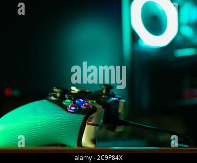 Close up of a game pad and a glass pc case with turquoise lighting Stock Photo