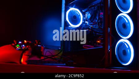 Glass pc case with blue lighting with a game pad on the foreground Stock Photo