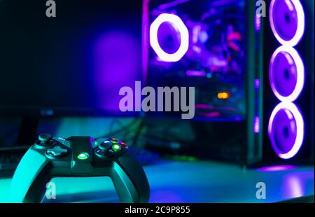 Game pad on with a glass pc case with purple lighting on the background Stock Photo