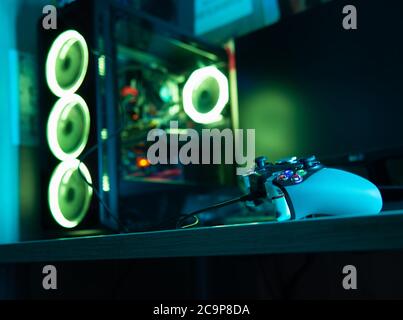 Game controller with a glass pc case with rgb lighting on the background Stock Photo