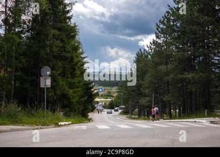 Zlatibor, Serbia - July 25. 2020 Asphalt road through dense pine forest and mountain with a dramatic sky in background in a natural resort on Zlatibor Stock Photo