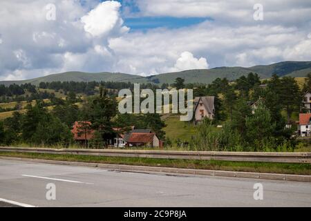 Zlatibor, Serbia - July 25. 2020 View of the mountain from the road and ethno village with wooden houses on the clearing in a natural resort Stock Photo