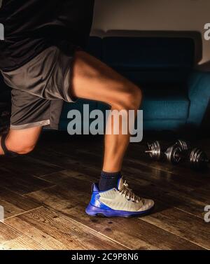 Side view of a man doing lunges during home workout Stock Photo