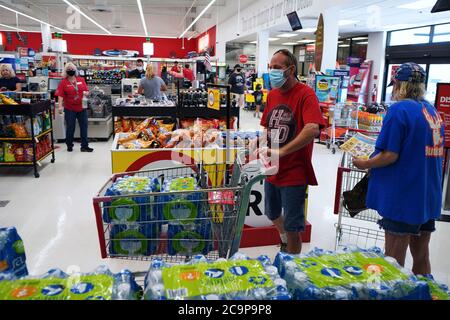 Cocoa Beach, United States. 01st Aug, 2020. August 1, 2020 - Cocoa Beach, Florida, United States - A shopper wearing a protective face mask during the COVID-19 pandemic fills a grocery cart with bottled water at a Winn-Dixie supermarket in preparation for the arrival of Hurricane Isaias on August 1, 2020 in Cocoa Beach, Florida. The storm is forecast to approach the coast of Florida tonight as a Category 1 storm and then parallel the Atlantic coast as it moves north. Credit: Paul Hennessy/Alamy Live News