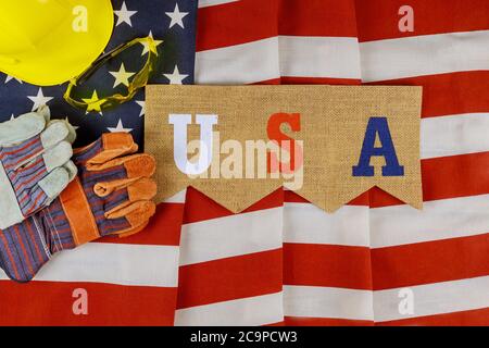 Flat lay composition with America happy labor day construction leather gloves safety and yellow helmet on United States America flag background Stock Photo