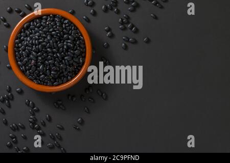 Top view of a bowl with black beans on a black background. Stock Photo