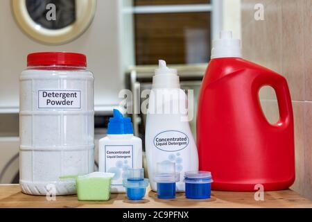 Various format of powder and liquid laundry detergent against backdrop of washing machine at home Stock Photo