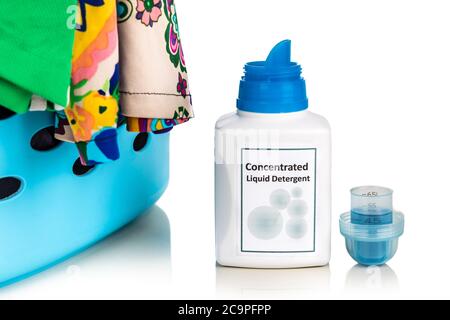 Tecnologically advanced compact concentrated laundry liquid detergent next to basket of clothes against white background Stock Photo