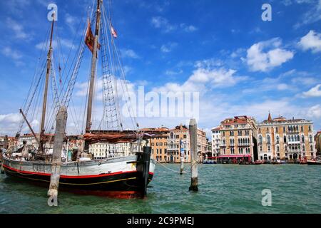 Old sailboat moored on Grand Canal in Venice, Italy. Venice is situated across a group of 117 small islands that are separated by canals and linked by Stock Photo