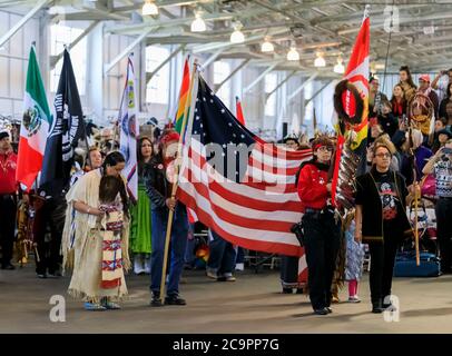 San Francisco, USA - February 08 2020: Native Americans dressed in traditional outfits carry traditional eagle staff and flags at powwow Grand Entry Stock Photo