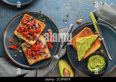 Vegetarian snack with tomatoes and avocado spread with herbs on bread , top view. Healthy food concept. Stock Photo