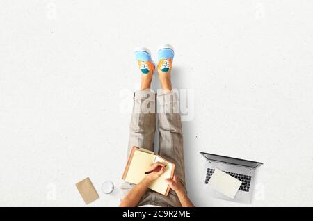 A young man sits on the floor and writes in a notebook Stock Photo