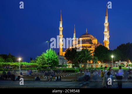 The Blue Mosque (Sultan Ahmed Mosque, Sultan Ahmet Camii) at night in city of Istanbul, Turkey, people, group of tourists relax on benches in Sultanah Stock Photo