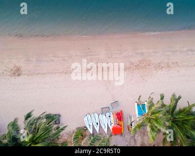Amazing drone view of coast with tropical trees casting shadows on turquoise water of sea during sundown Stock Photo
