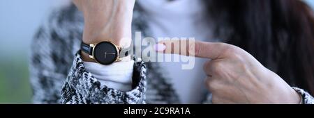 Displeased woman shows time on her wristwatch Stock Photo