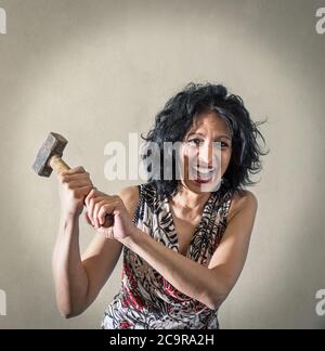 a Woman screaming with in hand a hammer Stock Photo