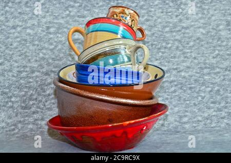 A small tower of high piled colourful crockery, bowls and cups Stock Photo