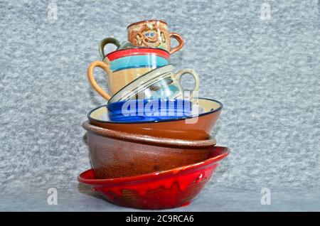 A small tower of high piled colourful crockery, bowls and cups Stock Photo